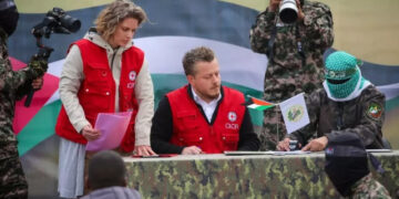 Član Crvenog krsta potpisuje dokumente pre nego što borci Hamasa predaju tri izraelska taoca u Deir el-Balahu