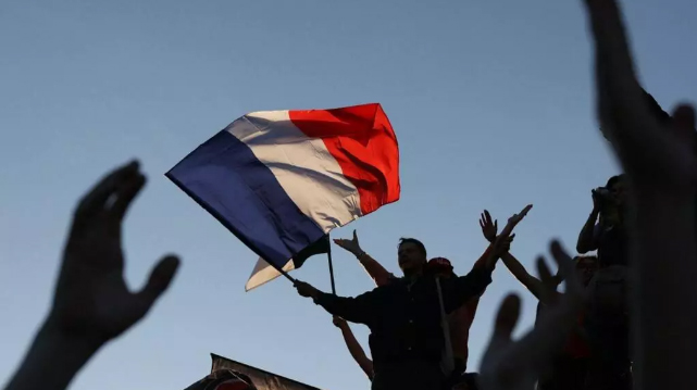 Učesnik skupa maše francuskom zastavom tokom izborne večeri nakon objave rezultata drugog kruga parlamentarnih izbora na Trgu Republike u Parizu 2024 foto Alain Jocard